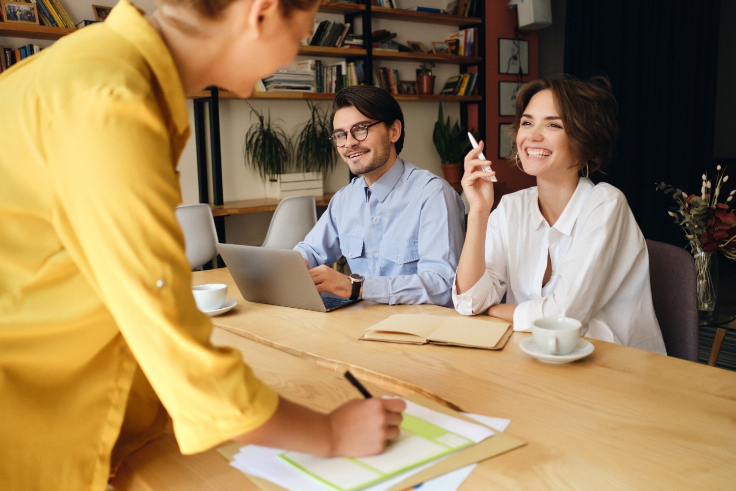 Cheerful business colleagues talking through work at a desk in a modern office