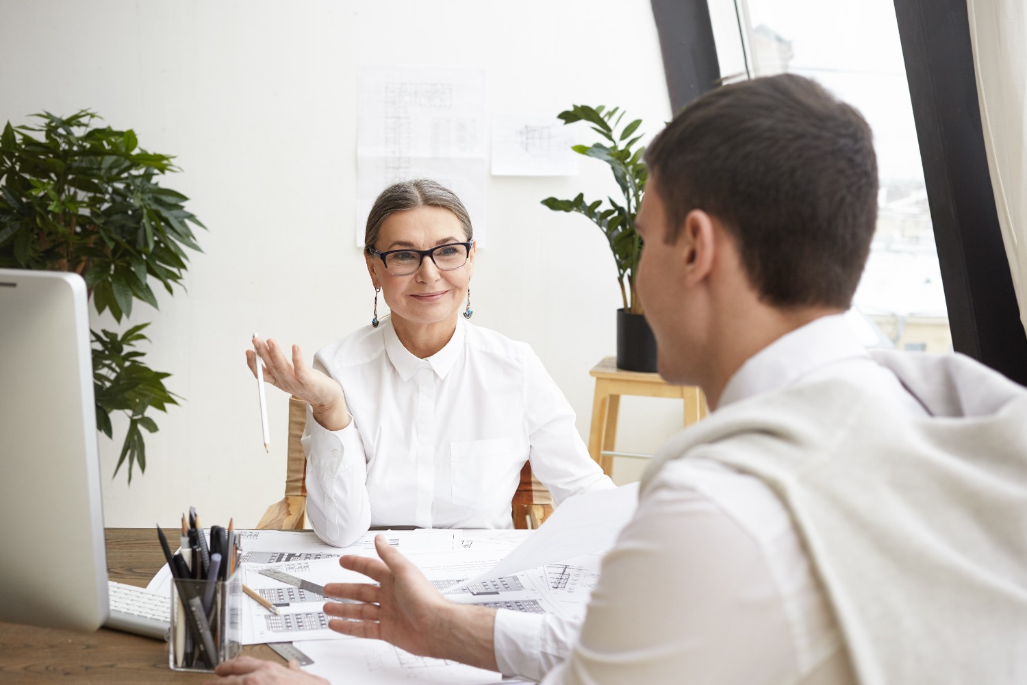 Senior analyst consulting with a young client in an office